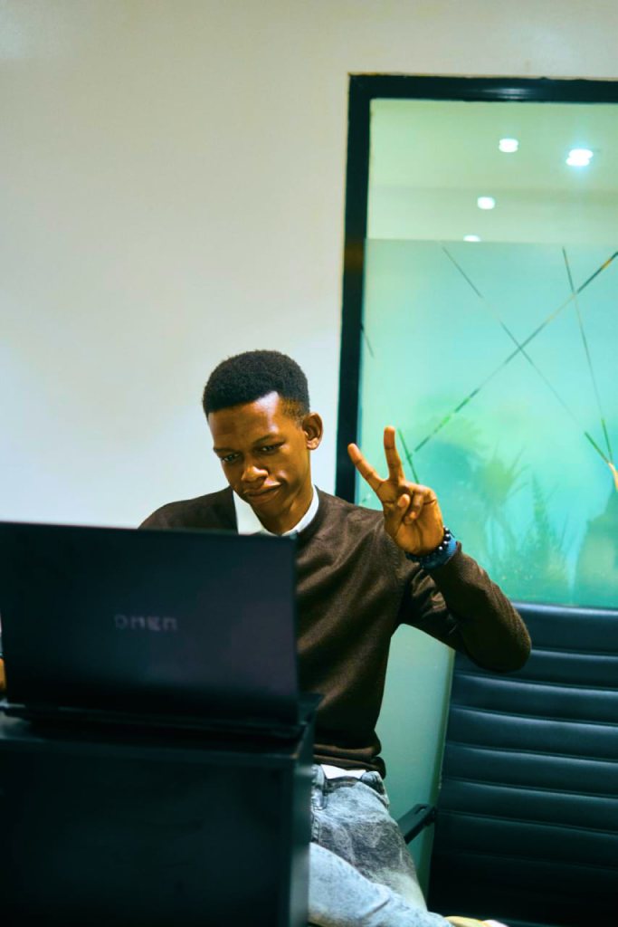 Ayobami at a laptop, making a peace sign
